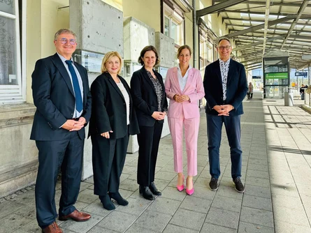 Männer und Frauen stehen an einem Bahngleis.