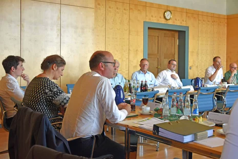 Männer und eine Frau sitzen an einem Konferenztisch.