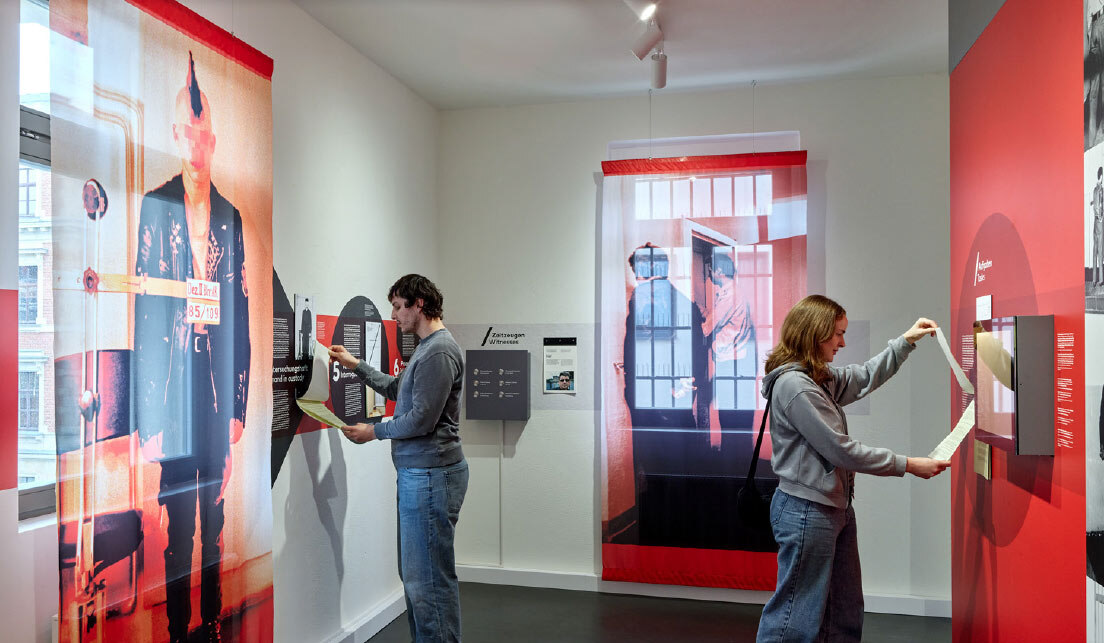 Eine Frau und ein Mann nehmen aktiv an einer Ausstellung teil. Dabei bedienen blicken sie auf einen Schreibblock.