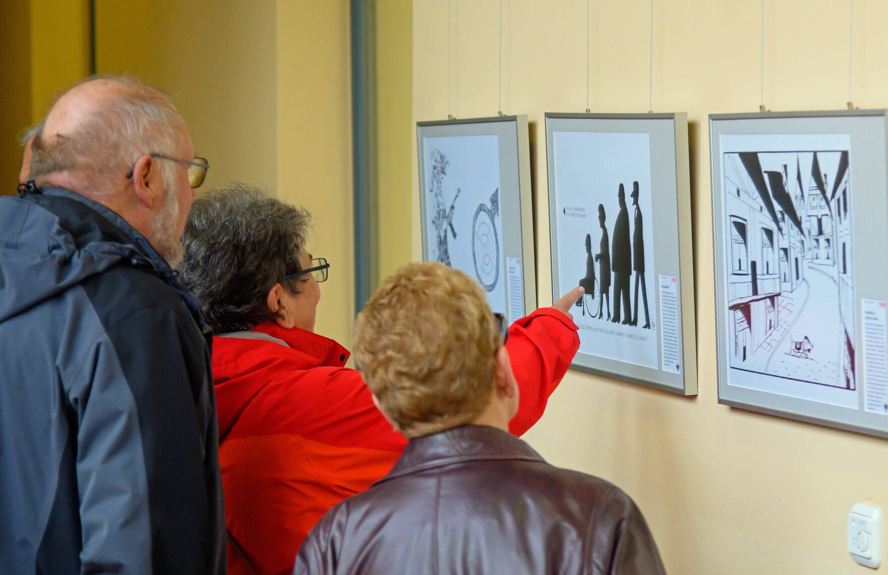 Gezeigt werden Besucher welche die Karikaturen zur Ost-West-Thematik betrachten.