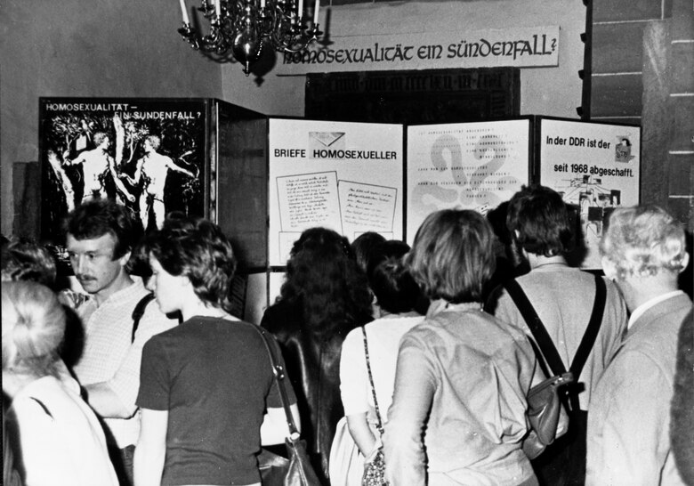 Männer und Frauen stehen vor einer Ausstellung.